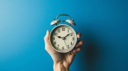 hand holding alarm clock , blue background alarm clock , urgency alarm clock image , time management image
