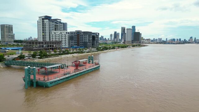 Aerial of Phnom Penh ferry terminal and Mekong riverfront buildings construction and development
