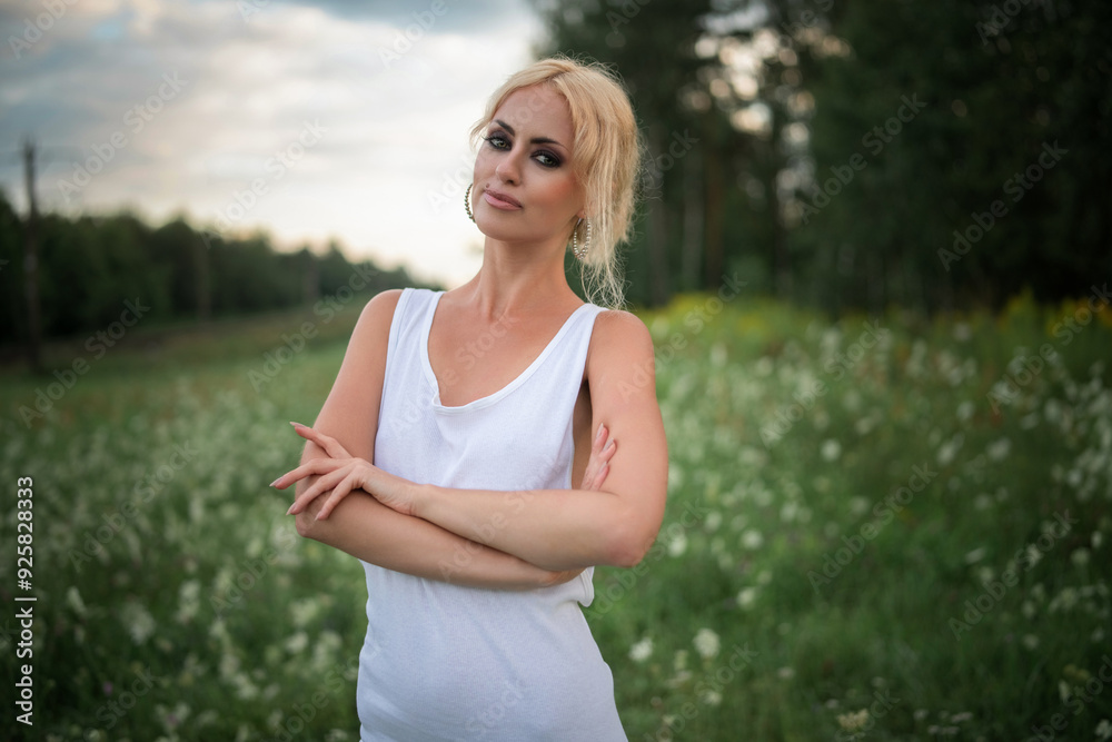 Wall mural portrait of a young beautiful blonde green-eyed girl in nature.