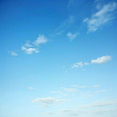 Clear blue sky with scattered white clouds on a sunny day offering a serene and peaceful view of the atmosphere