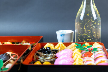盛り付けられたお節料理と金箔入りの日本酒