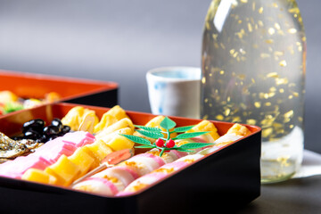 盛り付けられたお節料理と金箔入りの日本酒