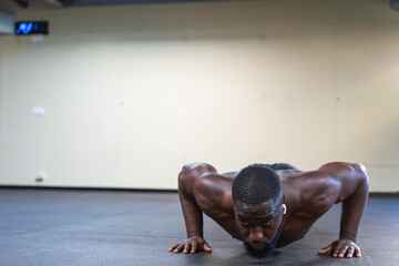 Shirtless black man doing push-ups at the gym