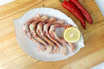 Fresh Raw Bone Chicken on White Plate with Herbs Chili as decor on wooden cutting board