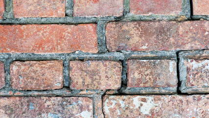 brick wall facade texture texture background. A textured background of decayed old red and white bricks in an exterior uneven wall of a house with dirty whitewashed worn plaster. Brick wall