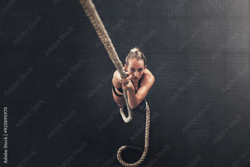 Wall mural Woman, bodybuilder and climb rope for fitness at gym for bodybuilding with strength and determination. Female person, muscles and strong on training, workout and exercise for health and above