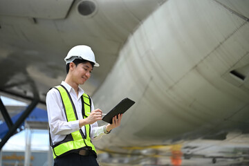 Male engineer or aviation technician using digital tablet in front of large aircraft engine © Prathankarnpap