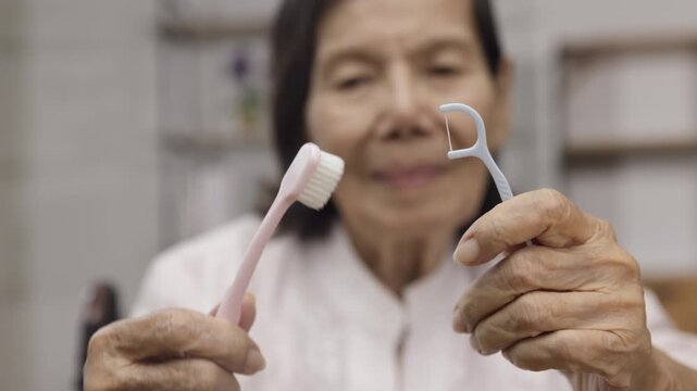 Elderly asian woman brushing teeth with brush with dental floss.