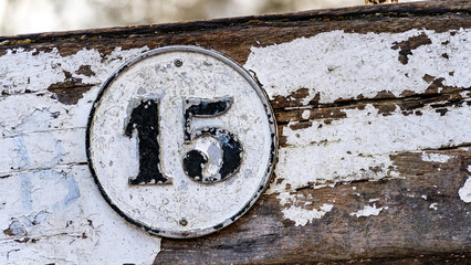 Distressed Number 15 Plaque on Weathered Wooden Surface with Peeling White Paint