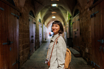 girl with a camera. A stylish girl with a backpack and a camera stands on the street of the old city.