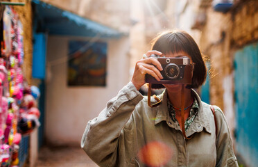 Beautiful woman takes pictures outdoors using an analog camera. travel to Arab countries.