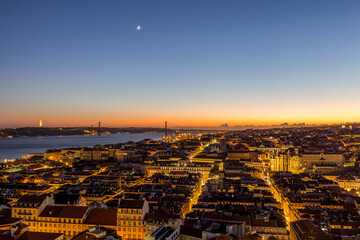 lights in the city of lisbon with the moon