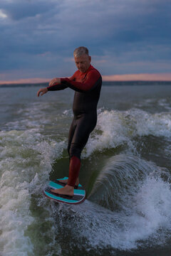 Man wake surfing in lake against sunset sky.
