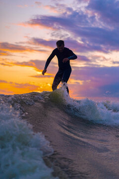 Man wake surfing in lake against sunset sky.