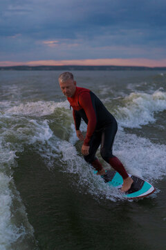 Man wake surfing in lake against sunset sky.