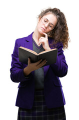 Young brunette student girl wearing school uniform reading a book over isolated background serious face thinking about question, very confused idea