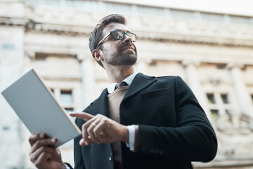 Fototapeta premium Business, man and looking away with tablet on street for connection, communication and networking as lawyer. Entrepreneur, employee and smile for career with social media post or email notification