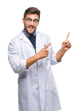 Young handsome man wearing doctor, scientis coat over isolated background smiling and looking at the camera pointing with two hands and fingers to the side.