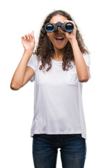 Young hispanic woman looking through binoculars surprised with an idea or question pointing finger with happy face, number one