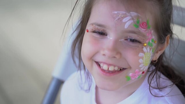 The artist makes a drawing on the girl's face with a face painting. 