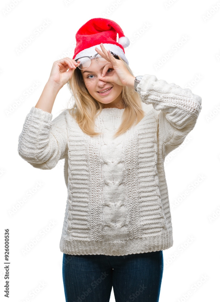 Poster Young caucasian woman wearing christmas hat over isolated background doing ok gesture with hand smiling, eye looking through fingers with happy face.