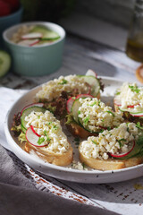 A plate with sandwiches with cottage cheese, radish and cucumber in rustic style