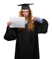 Young redhead woman wearing graduate uniform holding degree with angry face, negative sign showing dislike with thumbs down, rejection concept