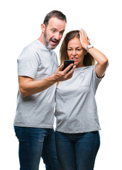 Fototapeta premium Middle age hispanic couple texting message on smartphone ver isolated background stressed with hand on head, shocked with shame and surprise face, angry and frustrated. Fear and upset for mistake.