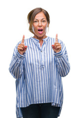 Middle age senior hispanic woman over isolated background amazed and surprised looking up and pointing with fingers and raised arms.