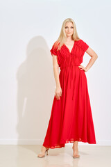 Fototapeta premium Blonde woman in red maxi dress posing indoors