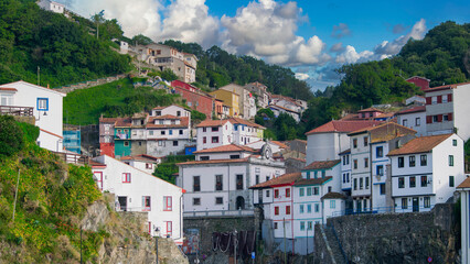 Fototapeta premium Casas a distinta altura en la hermosa villa costera de Cudillero en el litoral Cantábrico, norte de España. Con cielo editado