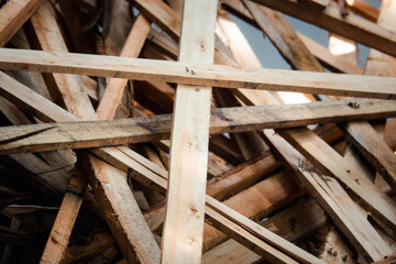 A pile of wood with many pieces of wood stacked on top of each other. The wood is of different sizes and shapes