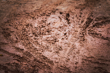 A muddy, dirty ground with tire tracks. The ground is brown and has a muddy appearance. The tire tracks are visible and add to the overall sense of dirtiness and weariness