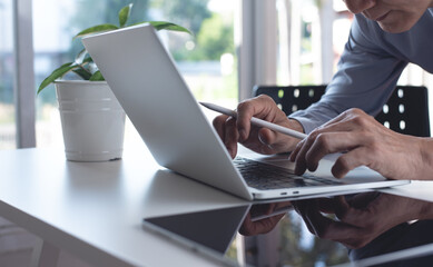 Close u, businessman browsing the internet, working on laptop computer and using digital tablet on office table