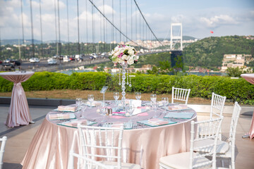 Elegant Outdoor Event Table with Bosphorus Bridge View in Istanbul: A beautifully set dining table...
