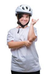 Young adult cyclist woman with down syndrome wearing safety helmet over isolated background with a big smile on face, pointing with hand and finger to the side looking at the camera.