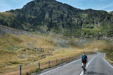 Female cyclist riding a road bike with a view of the mountains. Sport motivation.Female cyclist wearing a cycling kit and helmet. Carpathian Mountains, Transfăgărășan road in Romania.