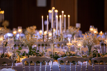 A long, elegant wedding table decorated with white flowers, candles, and gold accents. The romantic...