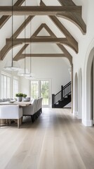 Fototapeta premium A cozy living room features light gray sofas, a wooden coffee table, and leads to a stylish kitchen and dining area with white walls and wooden beams