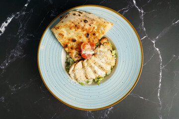 Caesar salad with fried chicken slices, tomato, parmesan cheese, tomato and crispy focaccia
