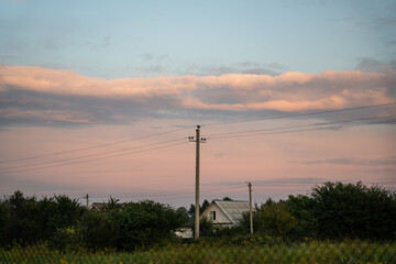 Obraz premium The support of power lines against the background of an orange sunset sky