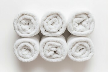 Six rolled towels in a variety of neutral tones, isolated on a white background, highlighting their soft and fluffy texture, perfect for spa or bathroom settings, selected focus

