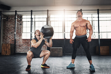 Fototapeta premium Men, friends and throw medicine ball at gym for bodybuilding with strength and determination. Workout, muscles and strong as body builder on training, fitness and exercise for health and self care