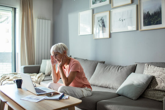Senior woman managing finances on laptop at home