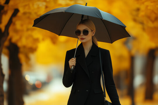 Adult woman in an autumn park with an umbrella, autumn business woman walk in the rain in a yellow October park - Powered by Adobe
