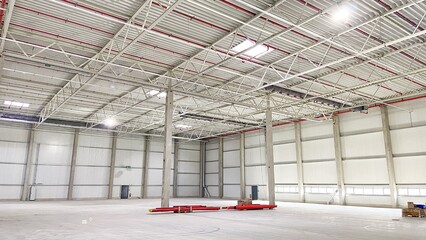 An empty warehouse with a high ceiling and concrete pillars. There are no people in the image.