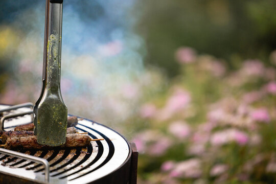 Juicy lamb kebabs are being grilled outdoors, using meat tongs.
