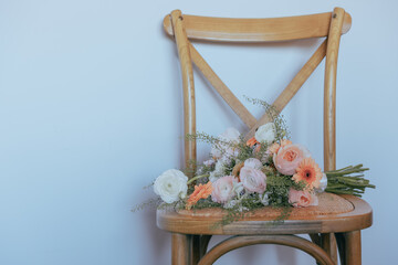 Bridal bouquet of flowers on a light wooden retro chair with white background