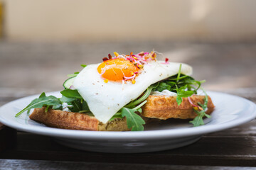 Waffles with egg and rocket. City breakfast outdoors local restaurant. Natural vegetarian food.
