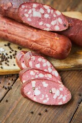 Sausage with lard lies on a wooden surface surrounded by spices. Meat production.